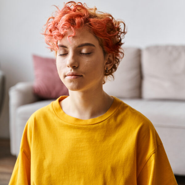 AVMH-EMDR beautiful extravagant queer person with red hair in vibrant yellow t shirt meditating at home