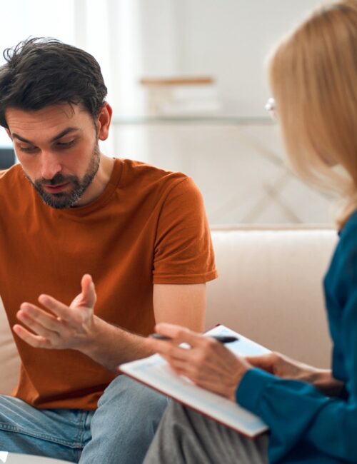 Young depressed man at the reception of a female psychologist during a mental health session. A man in frustrated feelings at a psychologist, being in a state of stress, talking about his problems.